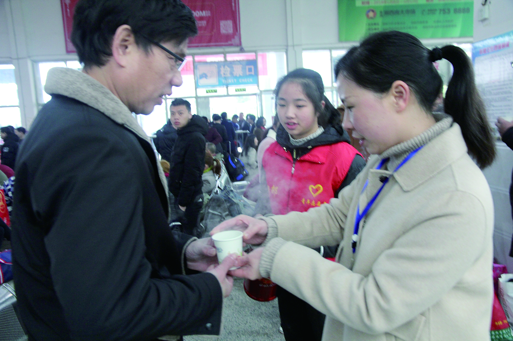 母女服務(wù)春運(yùn) 2月13日，記者在新邵分公司汽車站看到，該分公司安全科副科長李喜梅與其在新邵一中初中部1701班就讀女兒劉嘉怡在車站擔(dān)當(dāng)志愿者。李喜梅在候車室耐心為旅客釋疑解惑，劉嘉怡為旅客遞上一杯杯熱茶，有時(shí)母女也相互合作，其樂融融。 祖冠 攝影報(bào)道